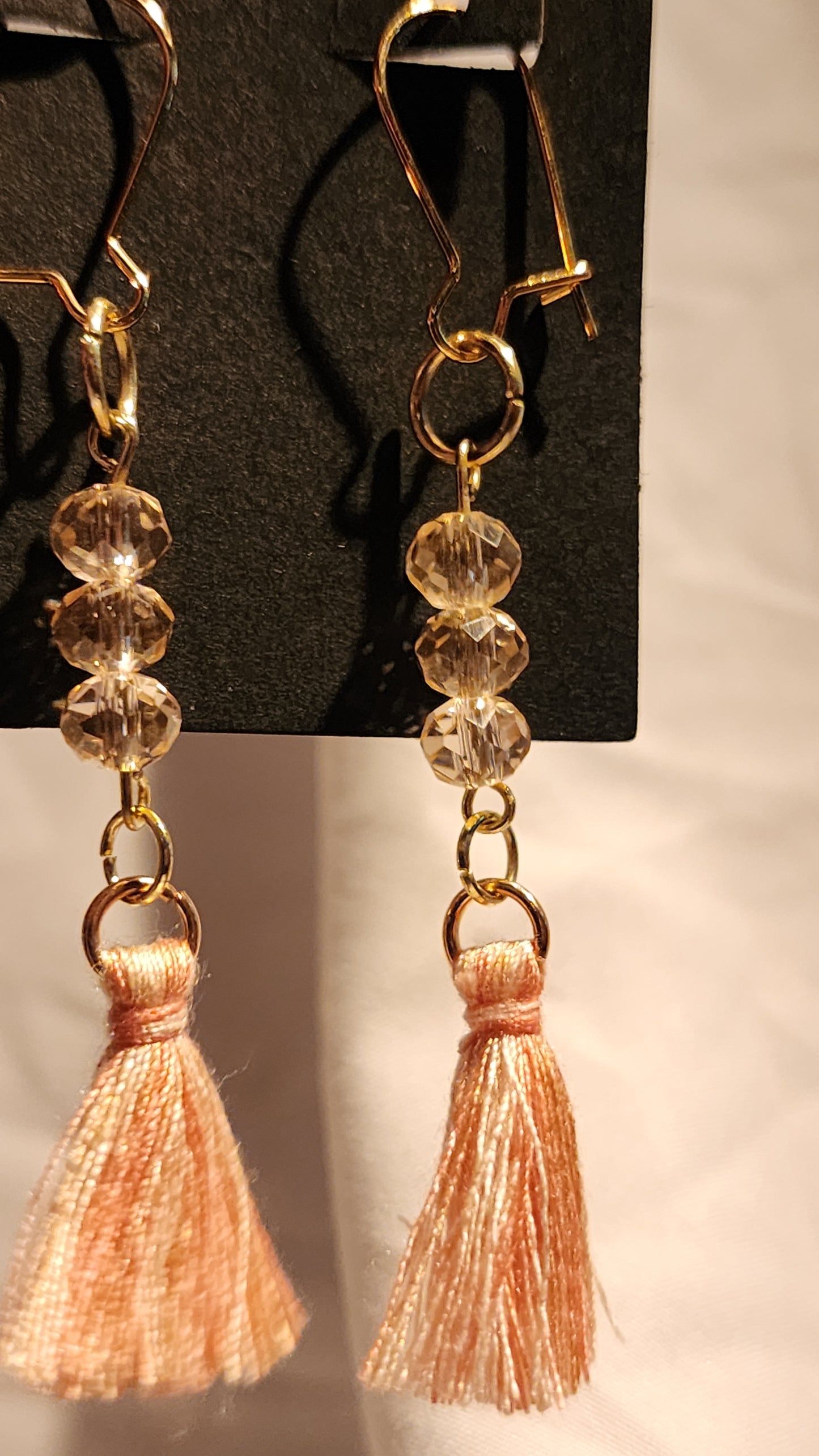 Dangle earrings with crystals and peach tassels.